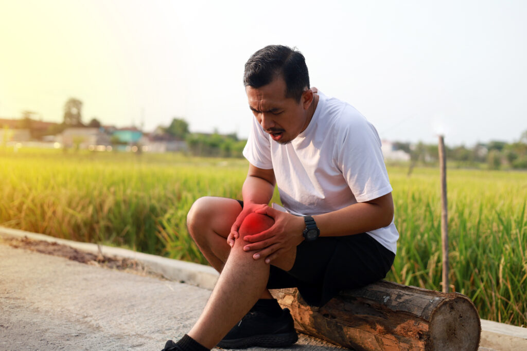 Asian man suffering from knee ache during doing outdoor exercise