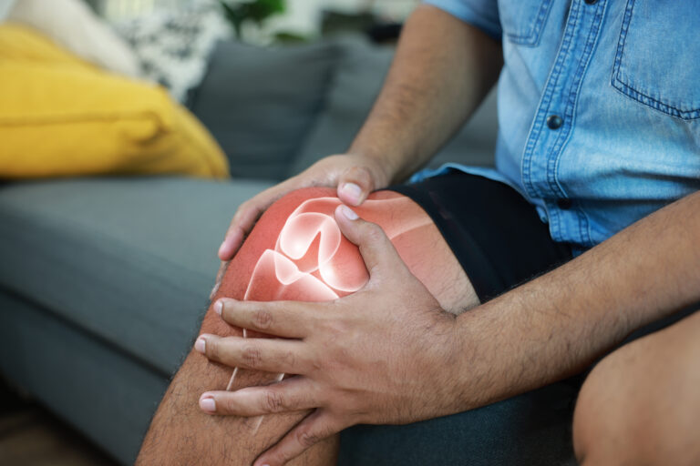 Person holding knee with ACL tear pain highlighted showing knee injury symptoms