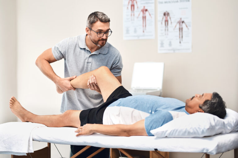 Physiotherapist providing knee pain rehabilitation therapy to a patient in a physiotherapy clinic.